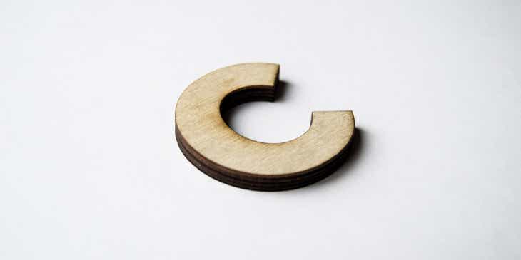 Een houten letter C getoond tegen een witte achtergrond.