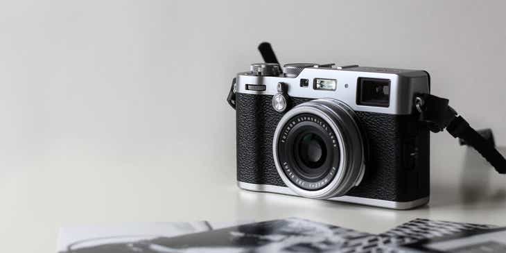 A camera neatly displayed on a white surface next to black and white photographs.
