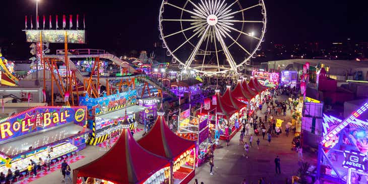 A carnival with a Ferris wheel and an assortment of stalls.