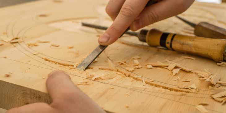 A carpenter chiseling a pattern in wood in a carpentry shop.
