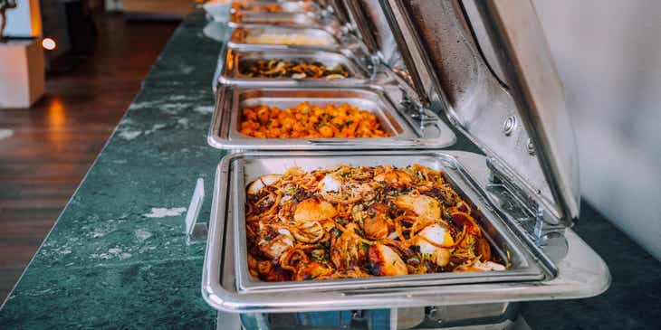 Een assortiment klaargemaakte maaltijden in voedselverwarmers bij een cateringszaak.