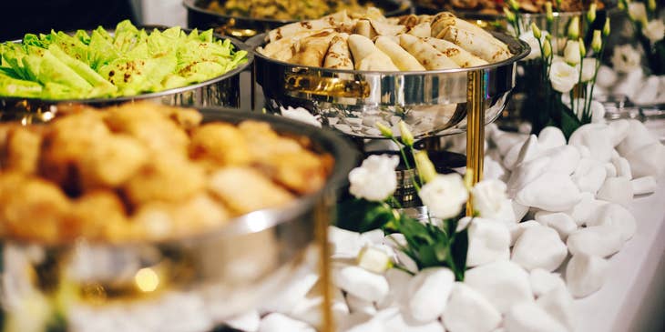 A buffet table with various food dishes set up by a catering company.