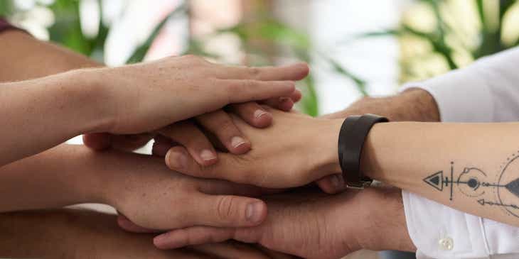 Grupa osób wspierających organizację charytatywną łącząca dłonie w geście jedności.