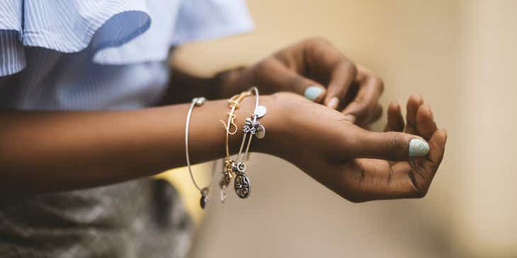 A person rearranging charms on their bracelet.
