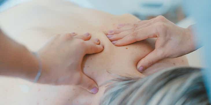 Ein Patient liegt auf dem Bauch und erhält eine Rückenmassage von einem Chiropraktiker.