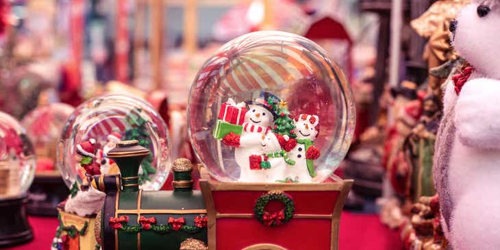 Verschiedenförmige Schneekugeln mit Schneemännern in einem weihnachtlich dekorierten Geschäft.