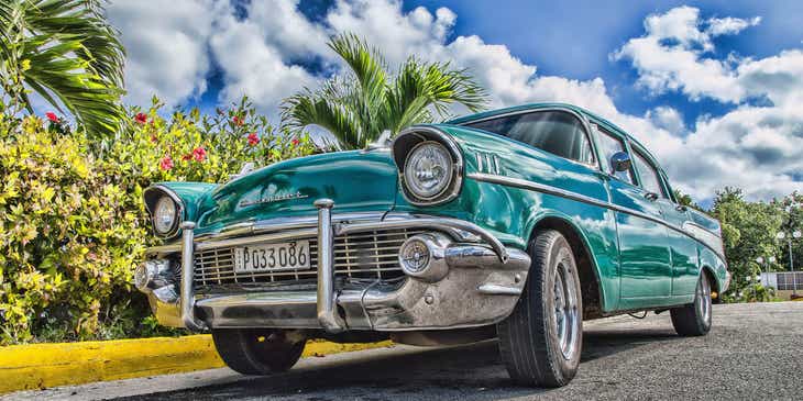 Een klassieke auto gefotografeerd tegen de blauwe lucht en palmbomen.