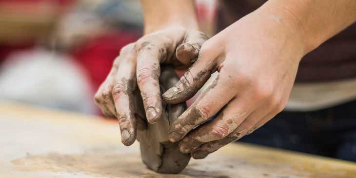 Mãos moldando um pedaço de argila.
