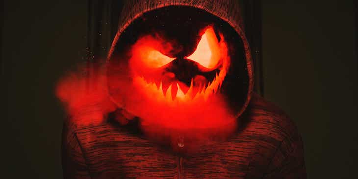 A creepy glowing pumpkin face in a red hoodie.