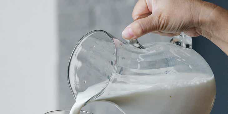 Una persona che versa del latte in un bicchiere.