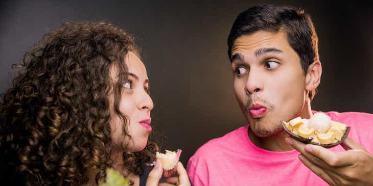 Ein Mann und eine Frau, die sich über eine Dating-App kennengelernt haben, essen Snacks und schauen sich dabei tief in die Augen.