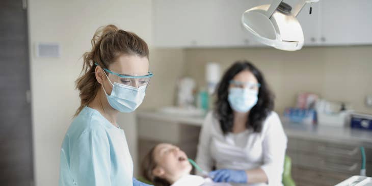 Two dentists performing dental work on a patient.