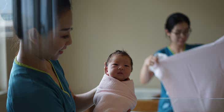 Una doula sosteniendo a un recién nacido en un logo de doula.