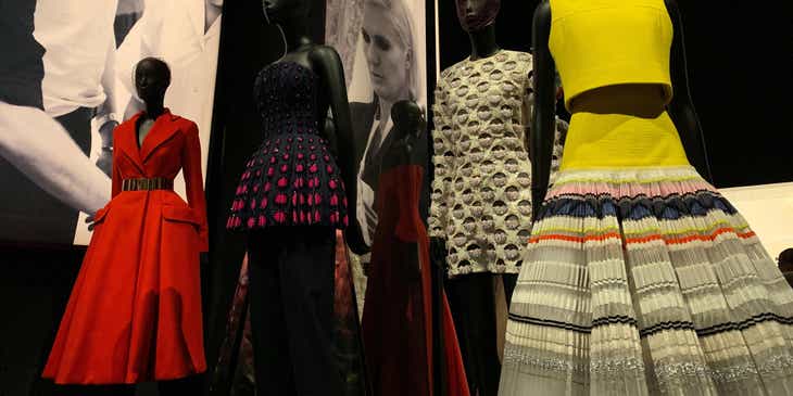 Eine Modeausstellung mit verschiedenenfarbigen Kleidern aus verschiedenen Epochen und großen Schwarz-Weiß-Postern.