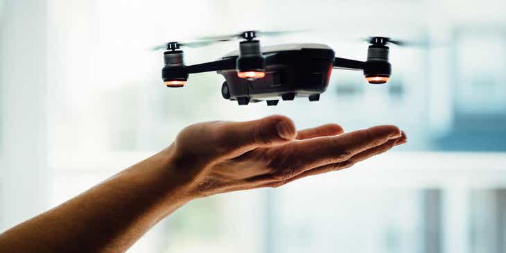 Um drone voando em cima de uma mão.