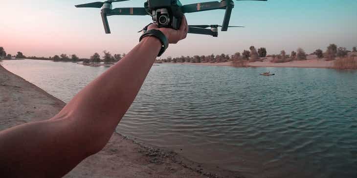 Osoba przygotowująca się do wypuszczenia drona, którym zamierza fotografować jezioro.
