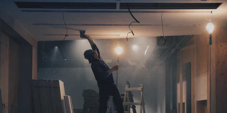 Un operaio che sta istallando una parete di cartongesso sul soffitto di un edificio.