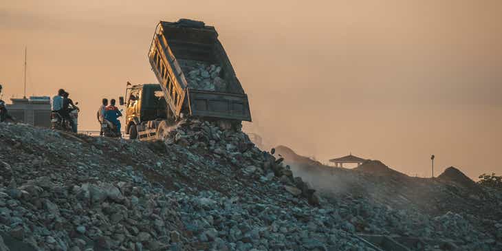A dump truck spilling its load into a landfill.