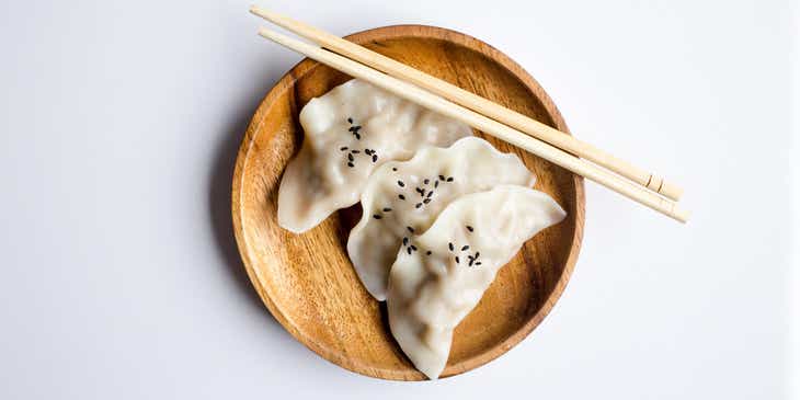 Dumplings y palillos en un plato de madera en un logo para dumplings.
