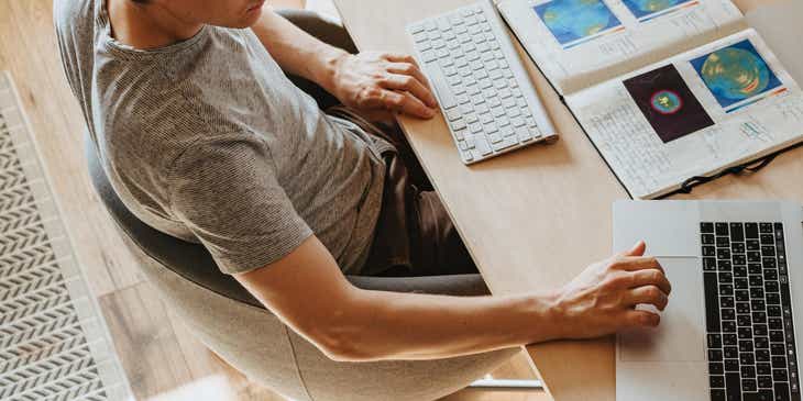 Eine Person sitzt an einem Schreibtisch und arbeitet effizient an zwei Laptops und einem Computerbildschirm.