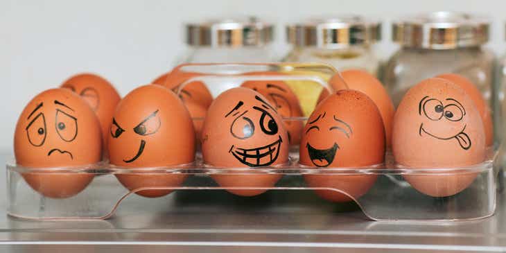 Des œufs dans un support avec des visages amusants dessinés dessus.