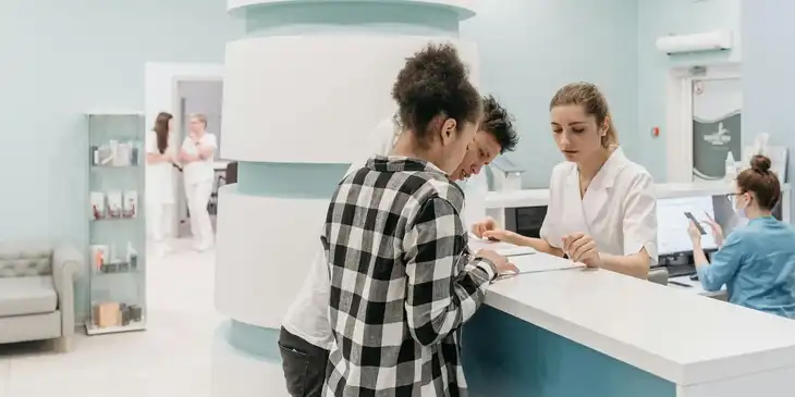 Imagen de la recepción de un hospital de cuidado de la salud con personas realizando un registro.