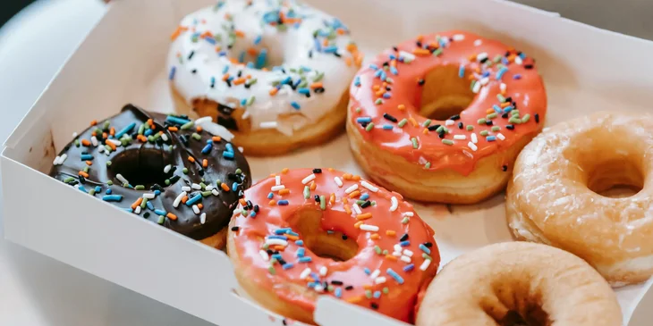 Una persona sosteniendo una charola de donas glaseadas.