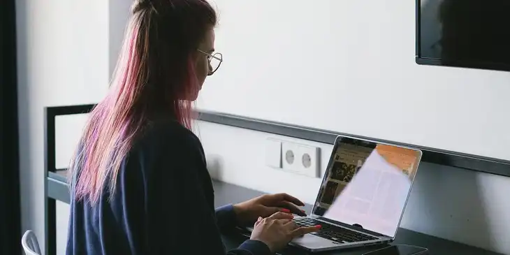 Una mujer leyendo un sitio web de noticias en una laptop.