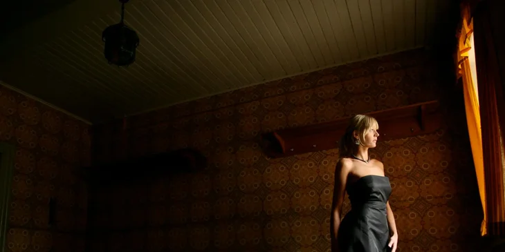 Una mujer vestida elegantemente de negro en una habitación oscura.