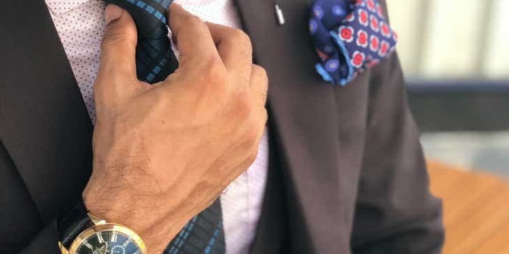 Un hombre de negocios de élite arreglando su corbata en un logo de élite.