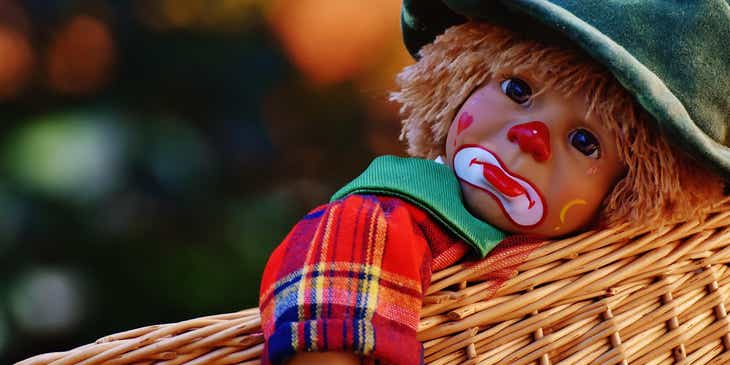 Eine traurig wirkende Puppe mit ausdrucksvollem Makeup liegt in einem Korb.
