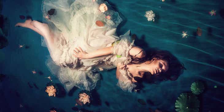 Eine Frau in einem traumhaften Kleid macht in einem flachen Becken ein Fotoshoot.