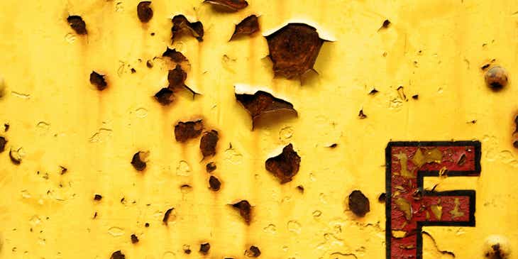 Una marca con una letra oxidada que se muestra en una pared amarilla desconchada en un logo con la letra "F".