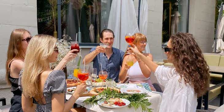 Een groep vrienden en familie die hun glazen opheffen tijdens een maaltijd in een familierestaurant.