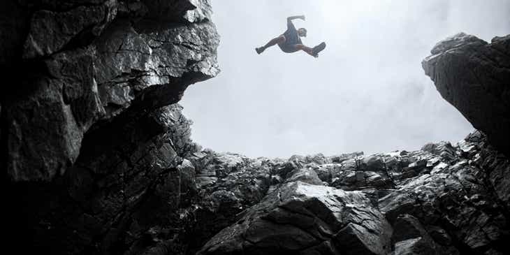A fearless person jumping from one rock formation to another.