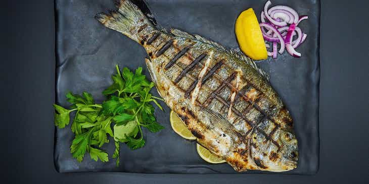 Un poisson grillé servi sur une assiette dans un restaurant de poisson.