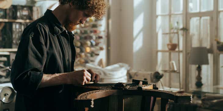 Um trabalhador restaurando uma mesa de madeira em uma empresa de restauração de móveis.