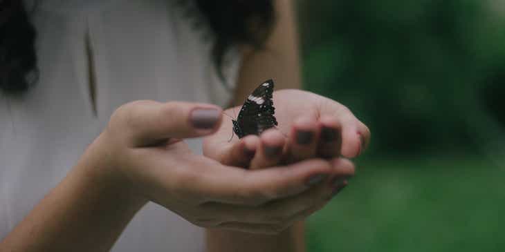 Een vrouw die teder een fragiele vlinder vasthoudt.