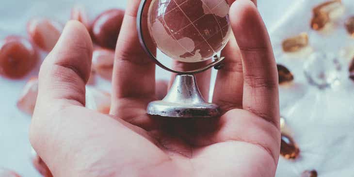 A person holding a mini globe in their hands.