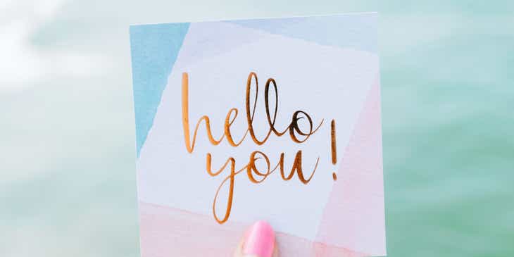 İngilizce "Merhaba sen!" yazan bir tebrik kartı tutan bir kişi.