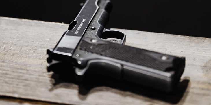 Sebuah senjata pistol di atas meja kayu.