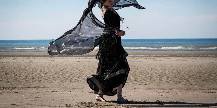 Een dansende zigeunervrouw gekleed in het zwart op een strand.