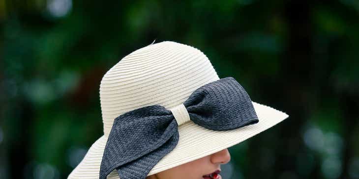 Seorang wanita mengenakan topi dengan pita besar.