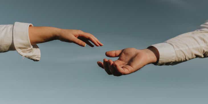 Zwei Personen reichen einander in einer vertrauensvollen Geste die Hände.