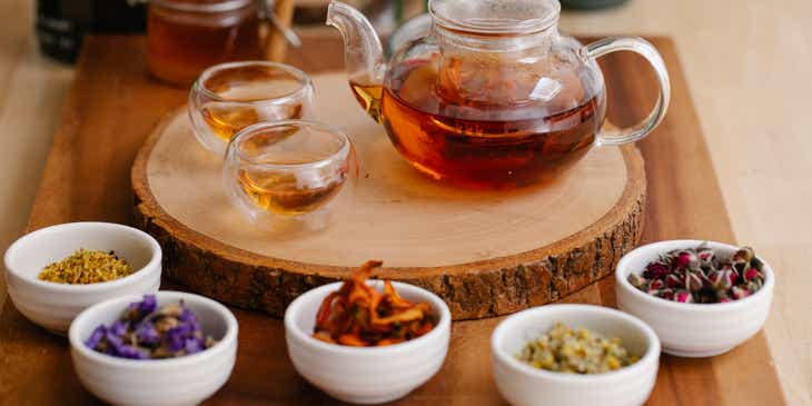 A fresh teapot of herbal tea displayed on a wooden board.