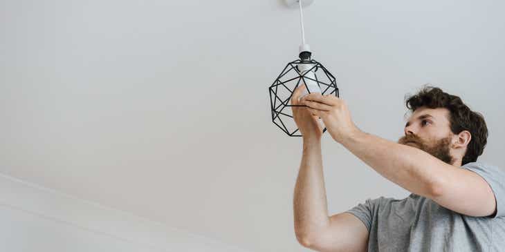 A home services employee installing a ceiling light.