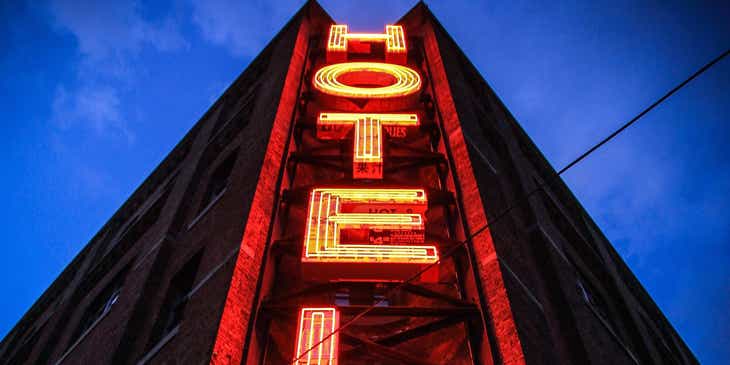 Un edificio alto e scuro con un grosso cartello luminoso che dice 'Hotel'.
