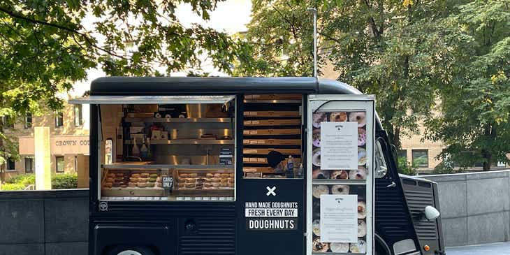 A new business startup selling donuts from a small black food truck.