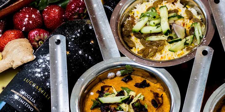 Mini ollas de plata llenas de curry en un restaurante de comida india