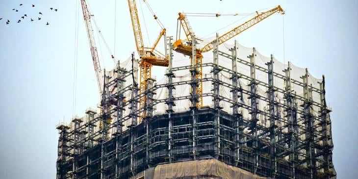 Drei Kräne bereiten auf einer Baustelle die erforderliche Infrastruktur für die Errichtung eines Hochhauses vor.